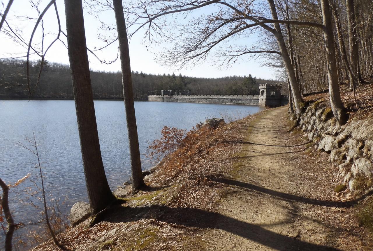 Wooded walking path beside a reservoir and stone dam in North Smithfield, Rhode Island